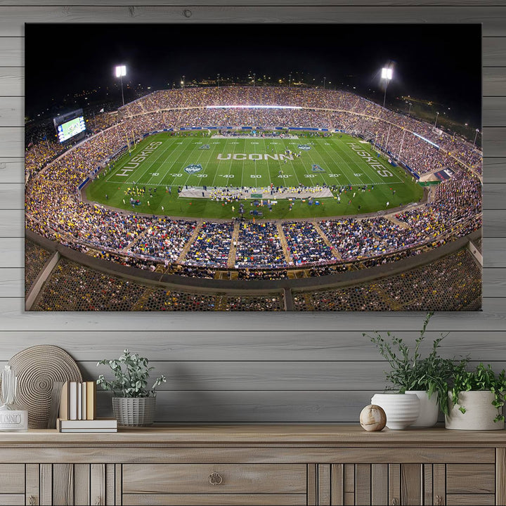 A large football stadium at night, featuring the UCONN Huskies, is depicted on the East Hartford Pratt & Whitney Stadium Wall Art Canvas Print.