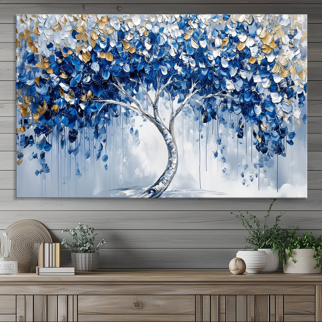 The Blue and Gold Abstract Tree Wall Art showcases a swirl trunk and features blue, silver, and gold leaves on a framed canvas print.