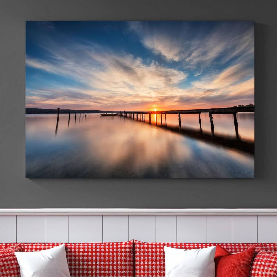 The tranquil sunset casting its glow over a peaceful lake with a long wooden pier captures the essence of coastal allure. The soft clouds mirrored in the water beautifully evoke the ambiance provided by the Sunset Pier Giclee Canvas Wall Art, a masterpiece designed for modern home decor and reminiscent of minimalist art.