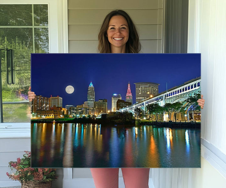 Cleveland City Lights Night Skyline Wall Art canvas showcases a moonlit cityscape reflected on water.