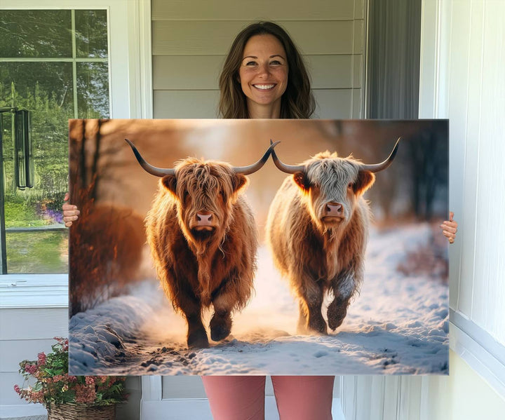 The wall art is a Scottish Highland Cow Horn canvas print featuring cows on a snowy path bathed in warm sunlight, serving as a rustic decor piece.