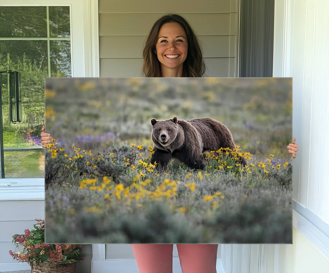 The "Grizzly 399 in Wild Flowers Wall Art Canvas Print" features a grizzly bear strolling through a field of yellow and purple flowers, beautifully showcased as a triptych. This handcrafted piece, proudly made in the USA, adds charm and sophistication to your space.