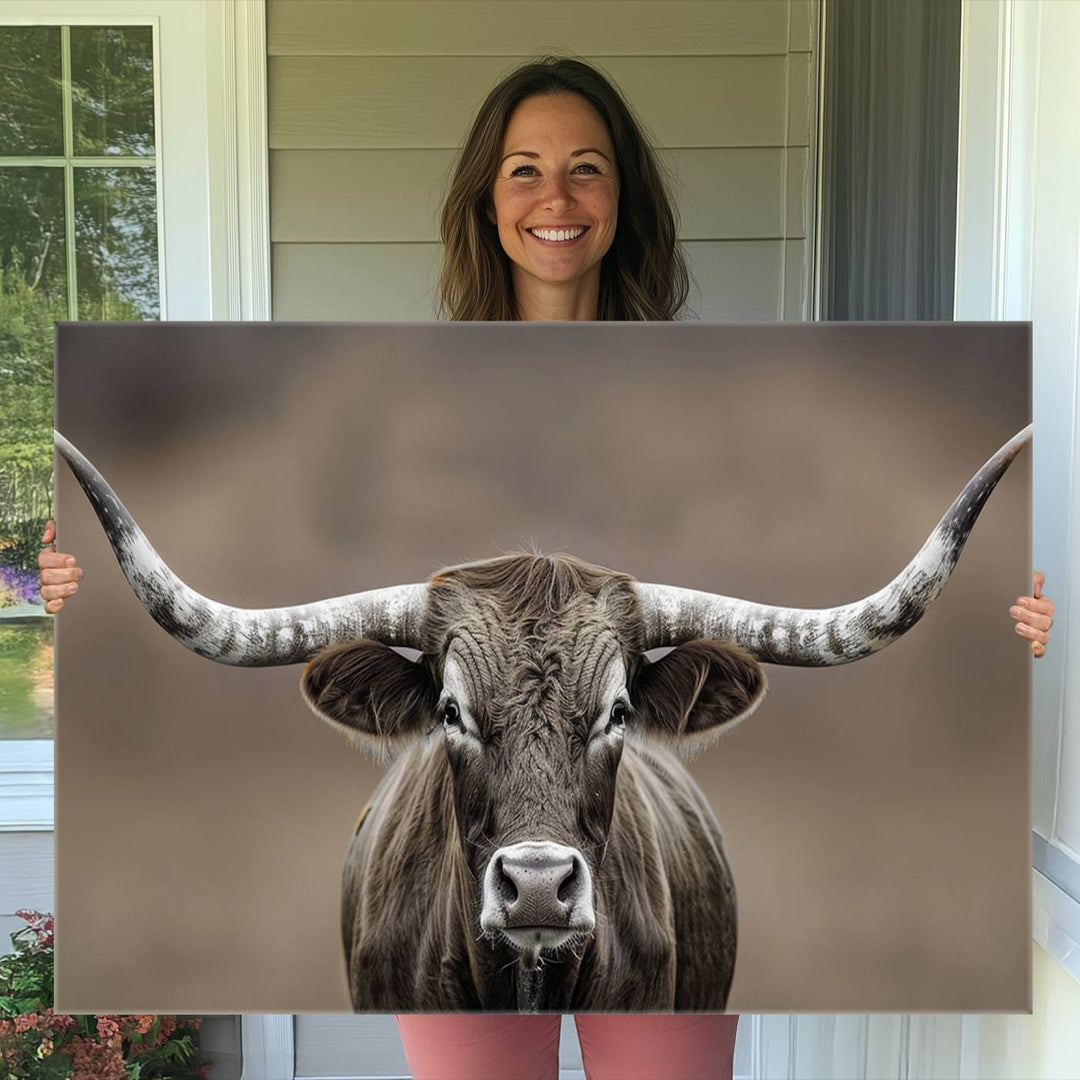 A close-up of a longhorn bull facing forward is featured in the Framed Texas Test-1, set against a blurred brown background.