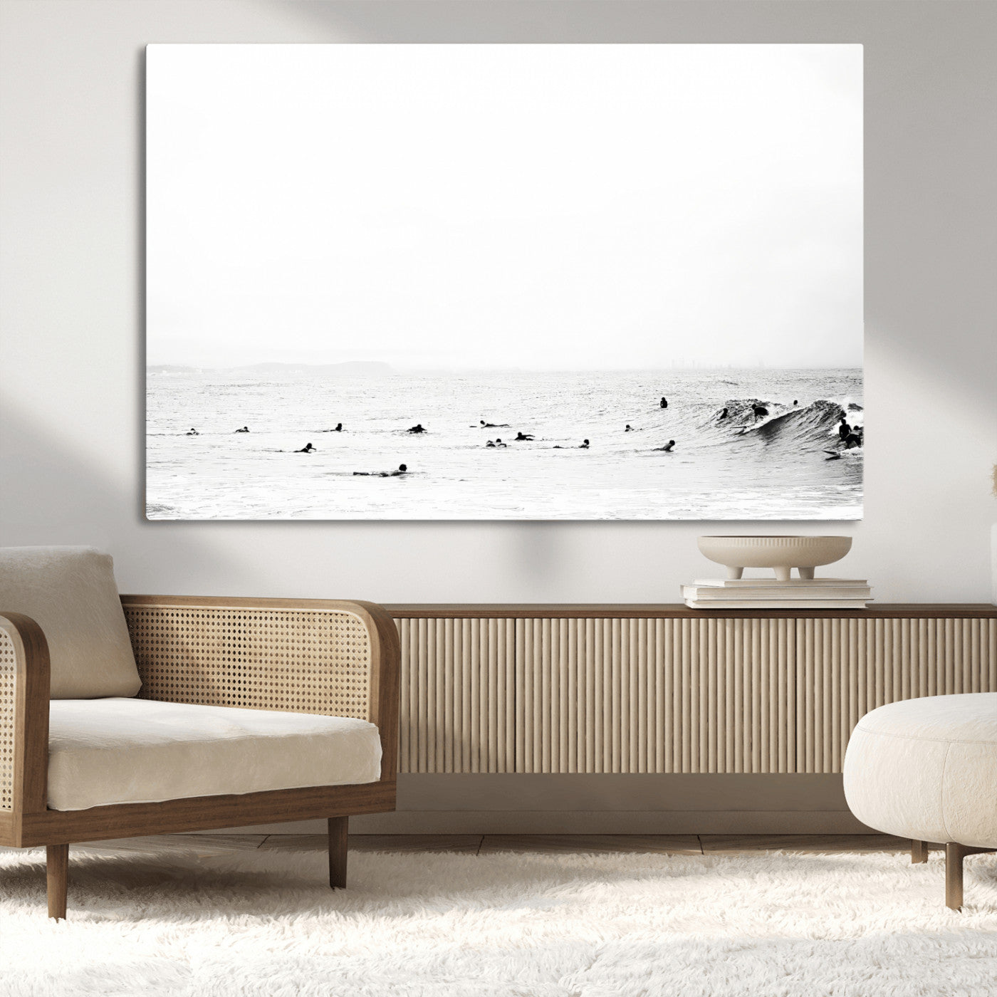 A group of surfers floating in the ocean, waiting for waves under a vast, moody sky, captured in black and white.