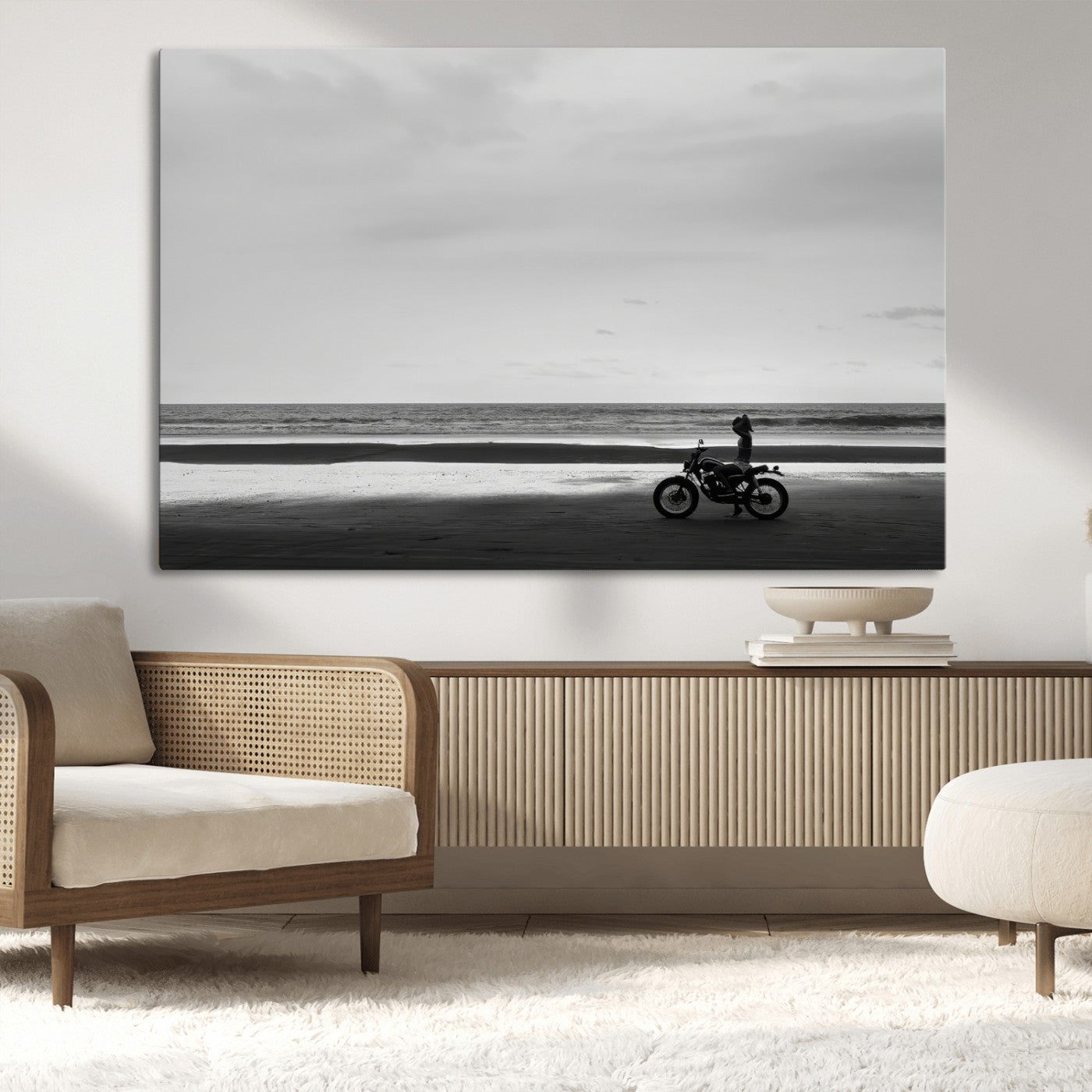 A motorcyclist on a vast beach, gazing at the ocean, capturing a moody and tranquil coastal adventure in black and white.