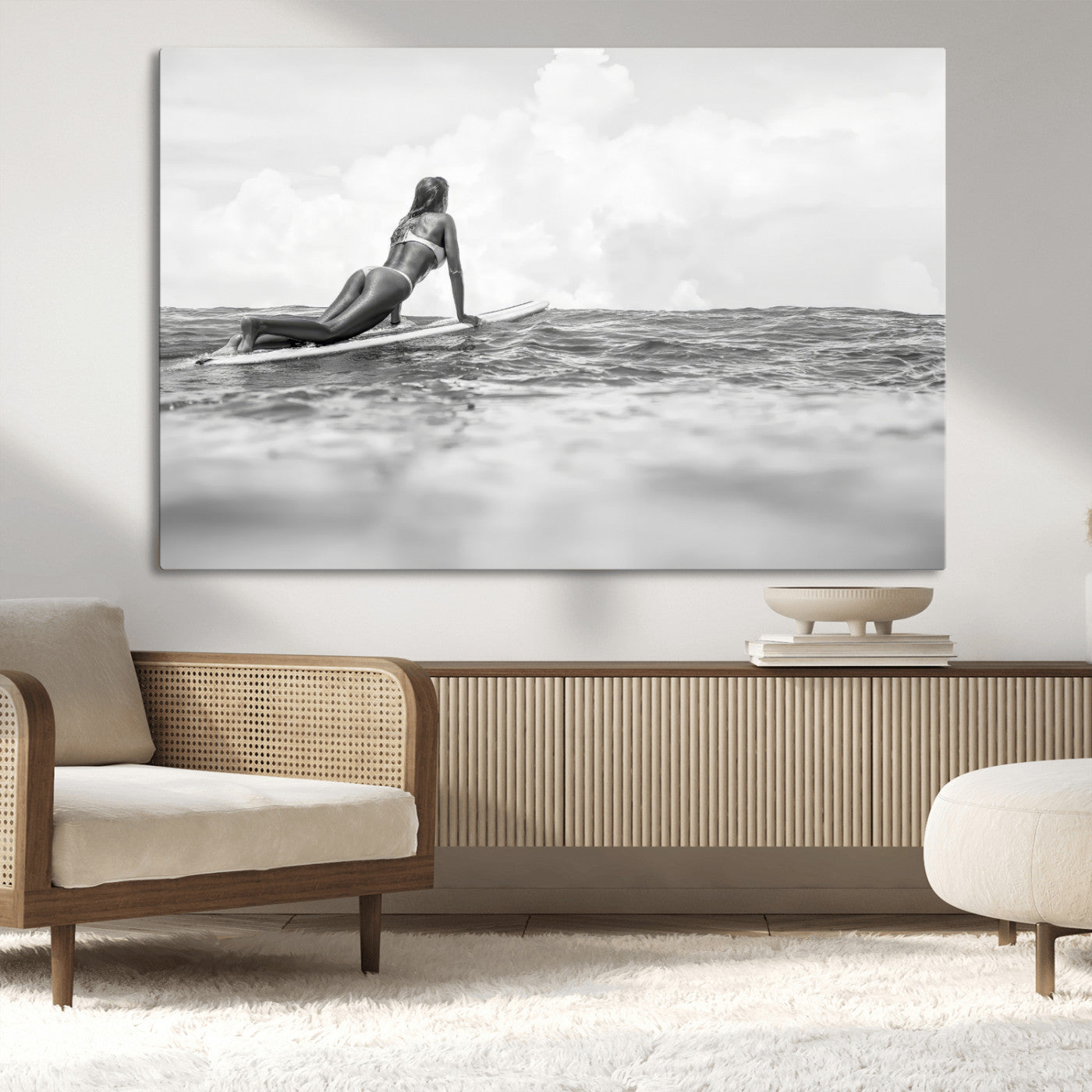 A black and white ocean scene featuring a surfer girl waiting on her board, gazing at the horizon, capturing a tranquil and adventurous coastal moment.