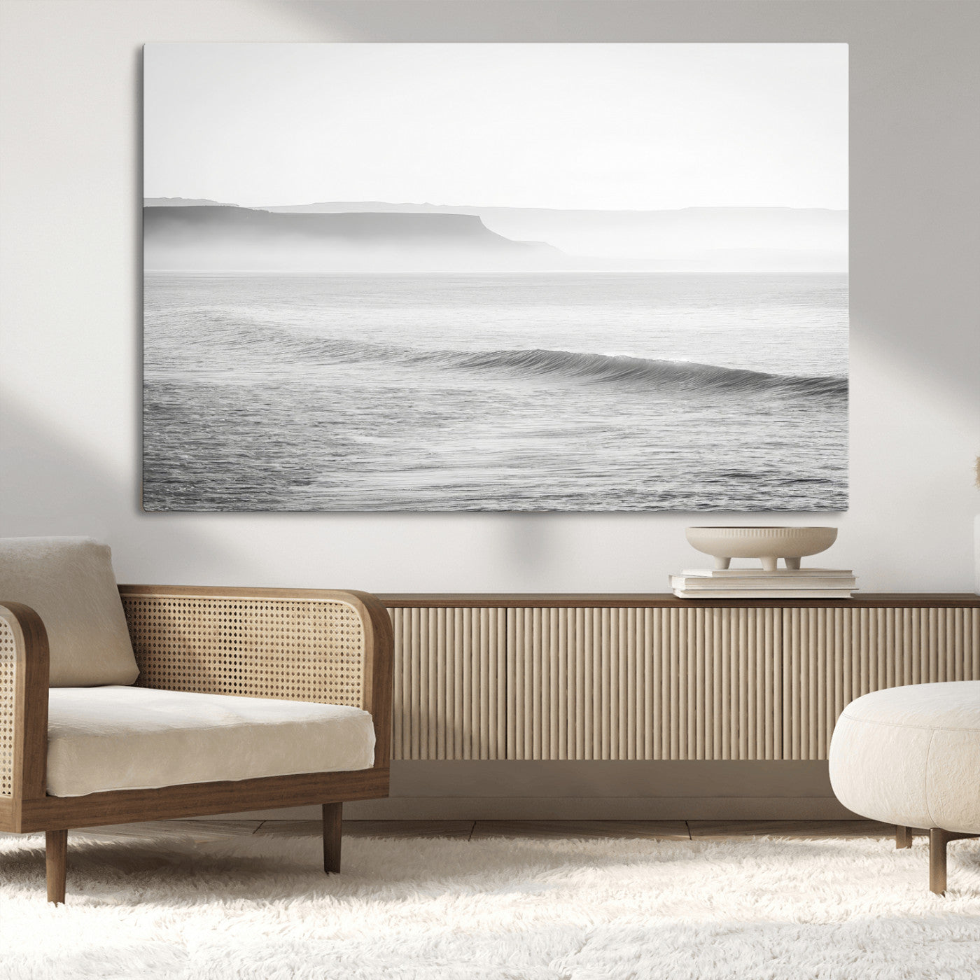 A black and white minimalist seascape featuring soft rolling waves and misty distant cliffs, creating a serene and timeless coastal atmosphere.