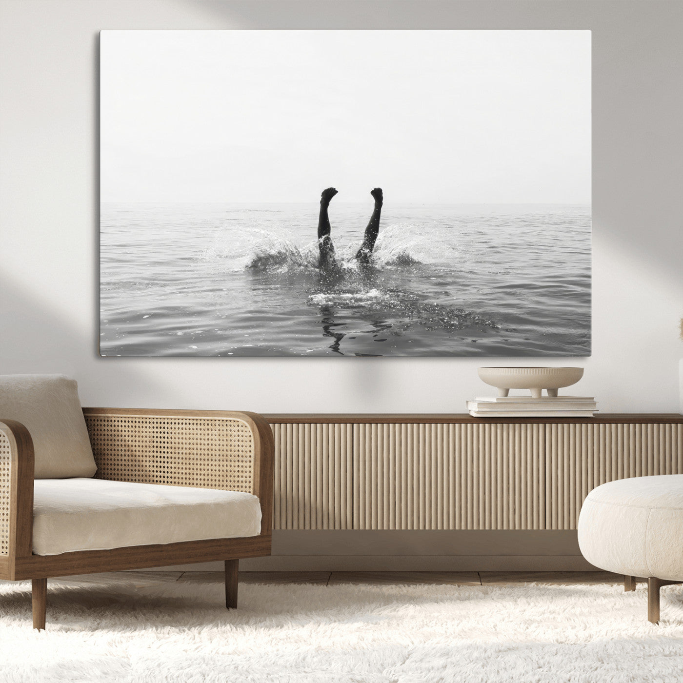 A black and white minimalist water scene capturing a playful splash as a swimmer dives upside down, creating a carefree and artistic aquatic aesthetic.