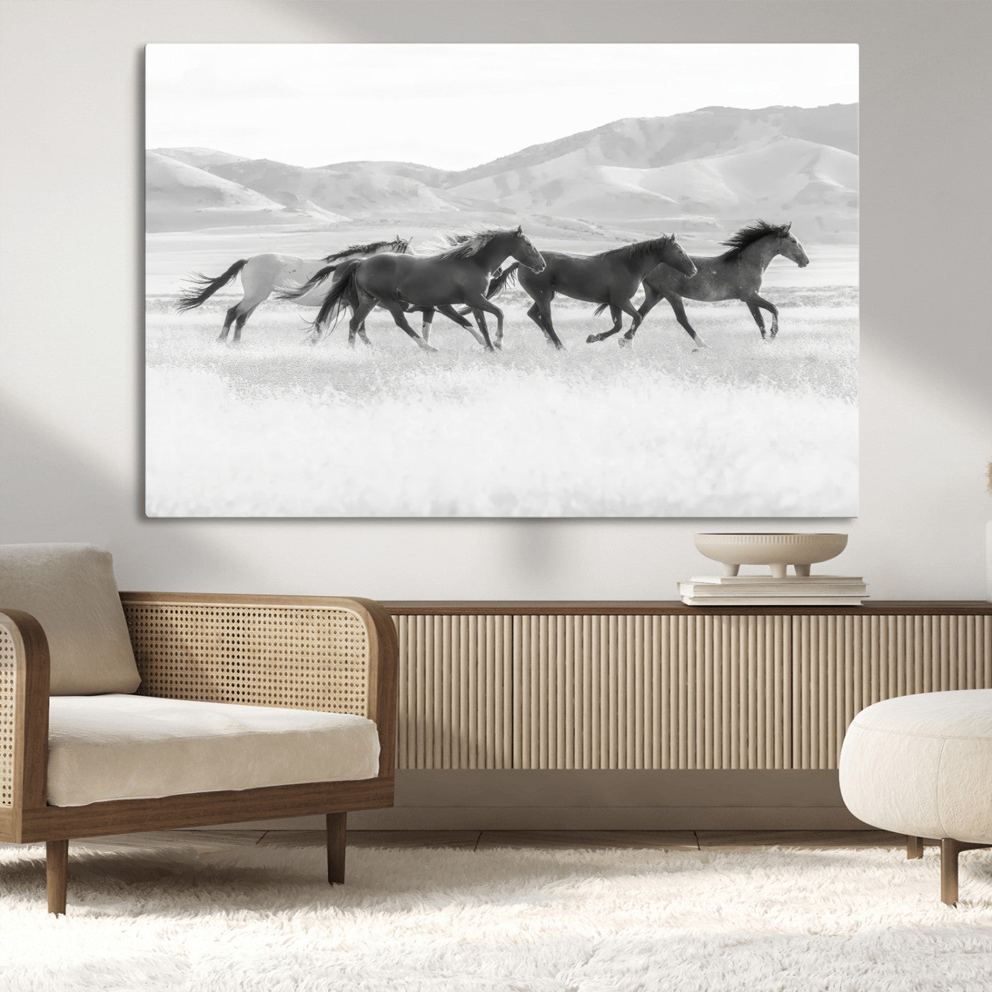A black and white image of wild horses running freely across an open grassland, capturing the power and beauty of untamed nature in a rustic western setting.