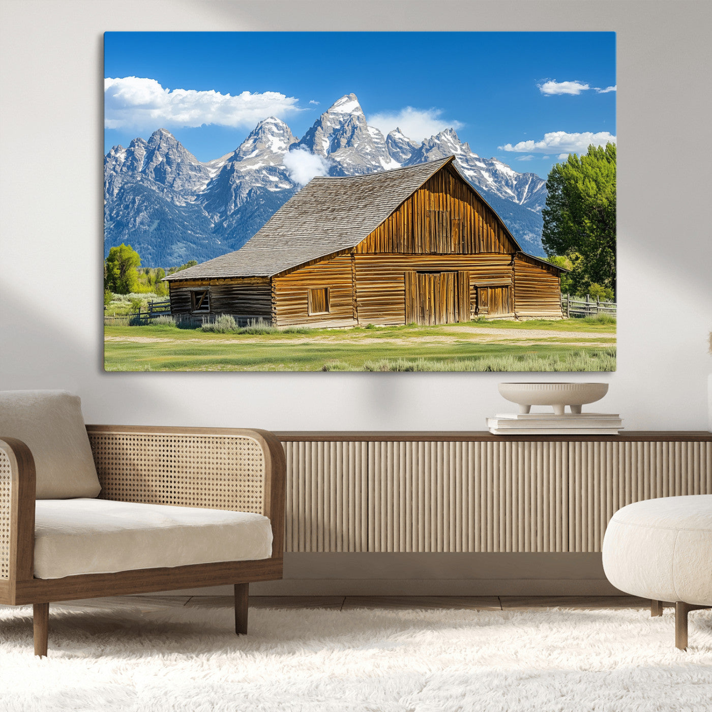 A rustic wooden barn sits in front of towering mountain peaks under a clear blue sky, perfect for farmhouse or cabin style interiors.