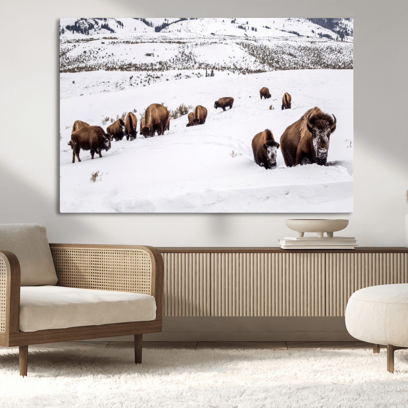 A herd of bison walking through deep snow in a mountain valley, perfect for rustic, cabin or western-themed wall decor.