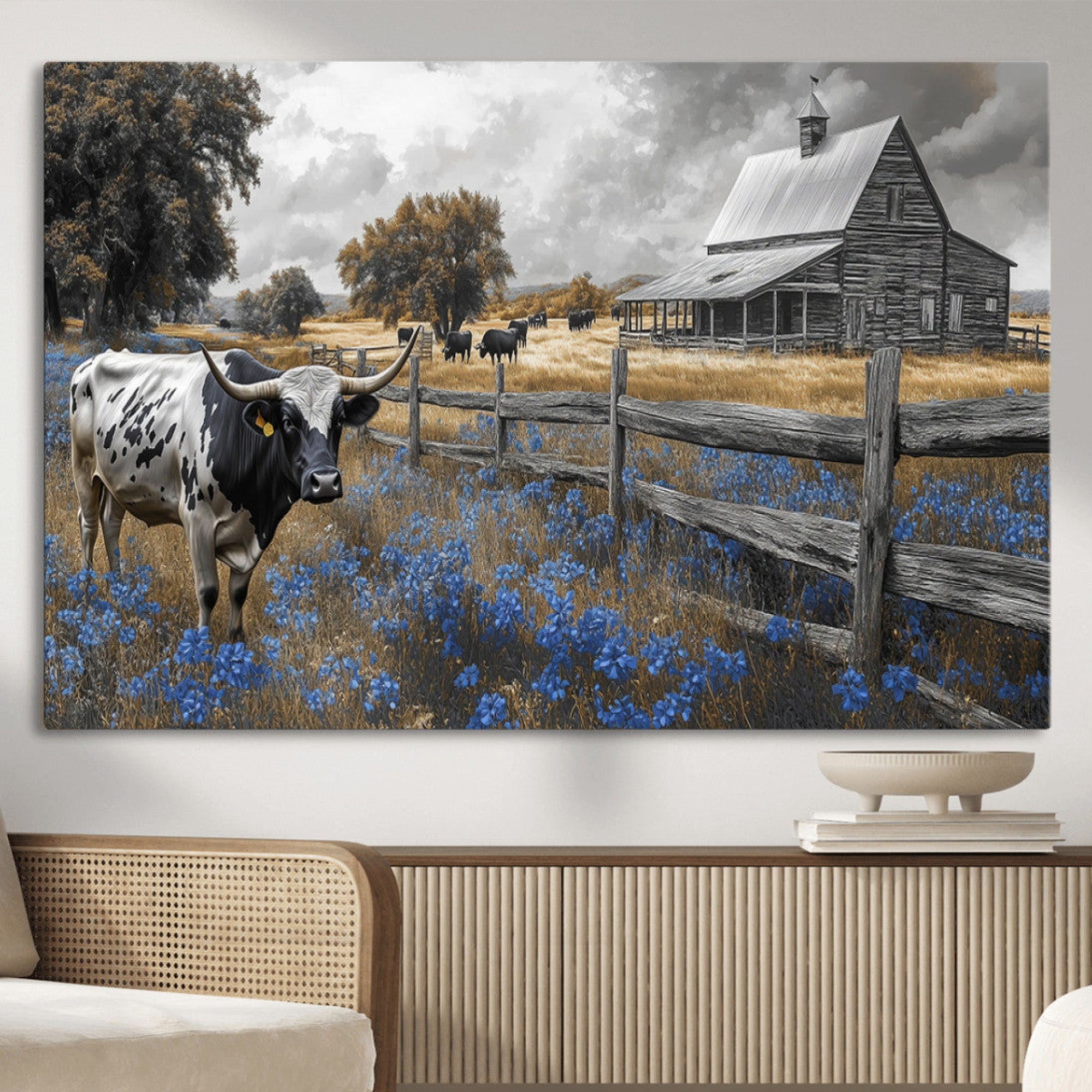 A Texas longhorn stands in front of a rustic barn and wooden fence, with bluebonnets and grazing cattle under dramatic skies.