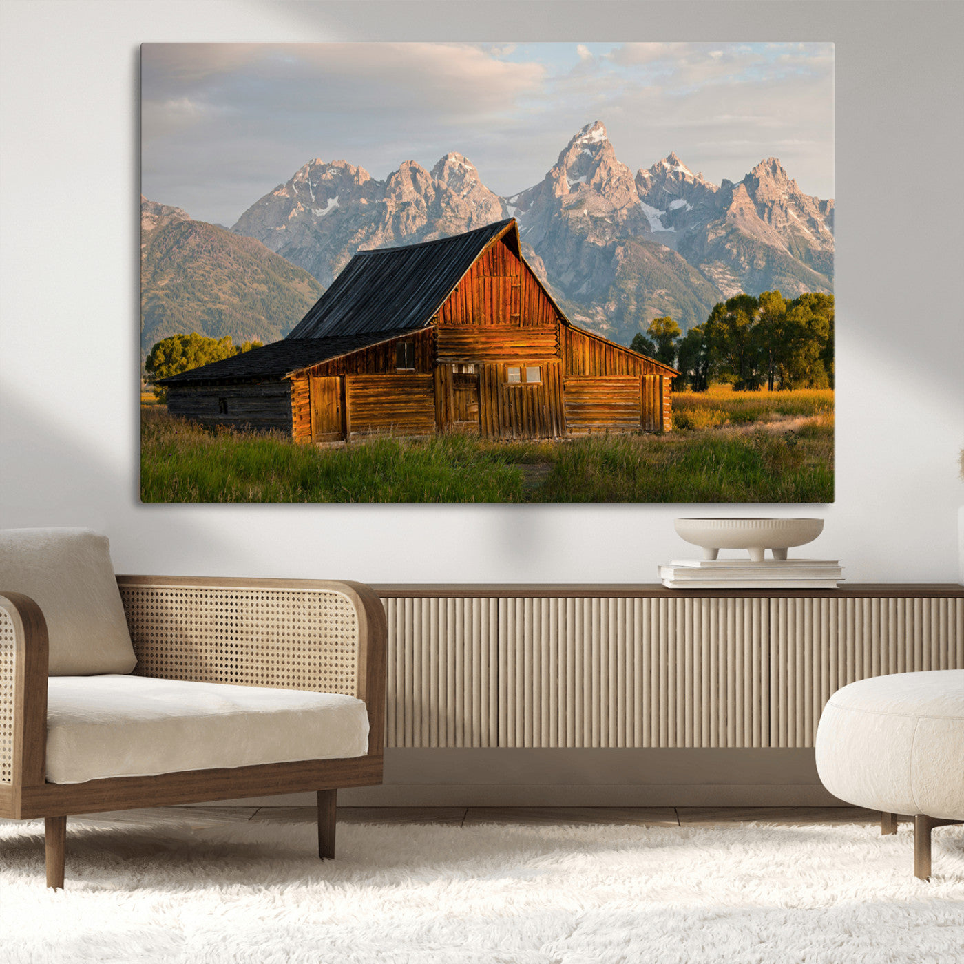 Rustic wooden barn set against towering mountain peaks under warm golden light, creating a peaceful Western countryside scene.