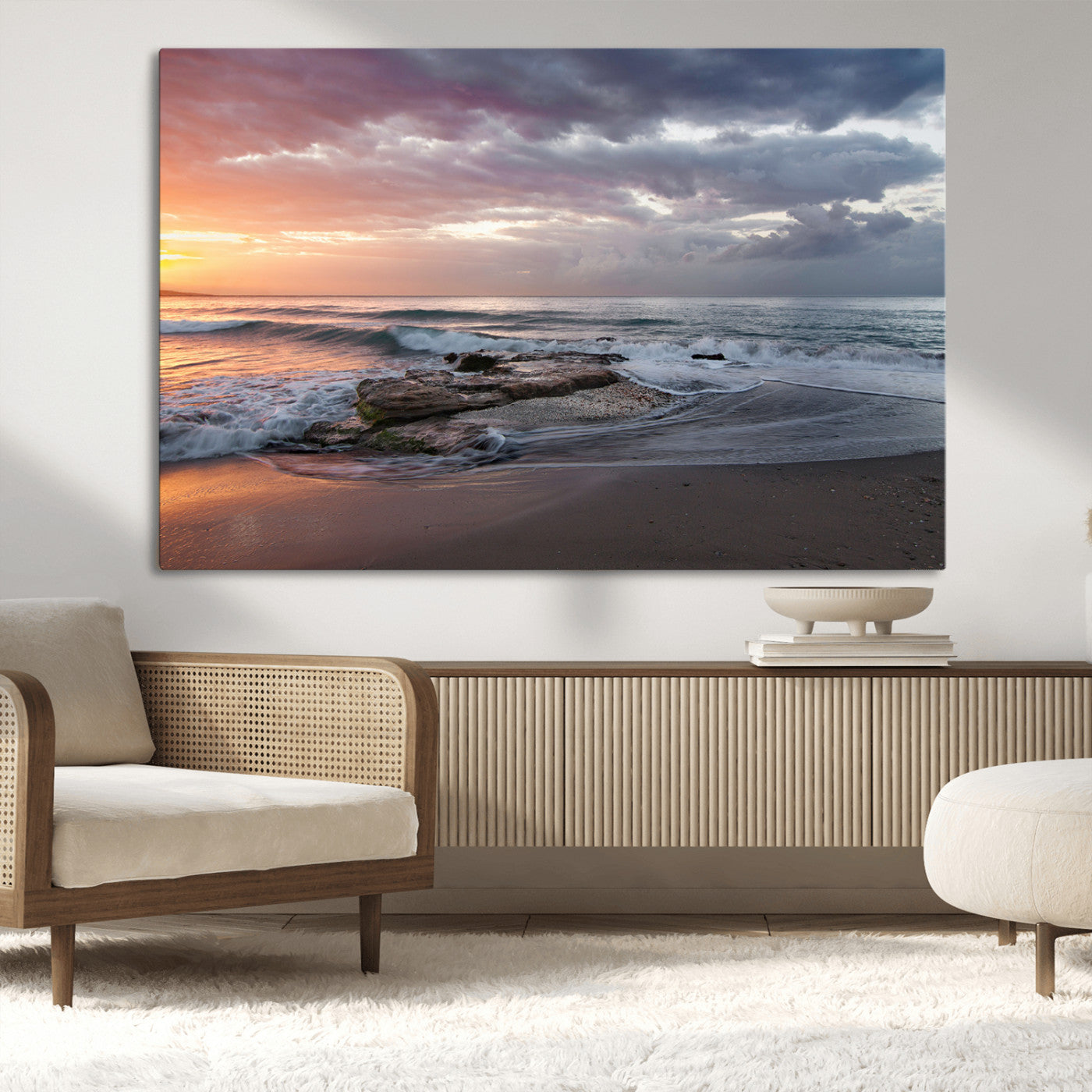 Dramatic sunset over a rocky shoreline with ocean waves gently reaching the sandy beach, creating a serene and coastal atmosphere.
