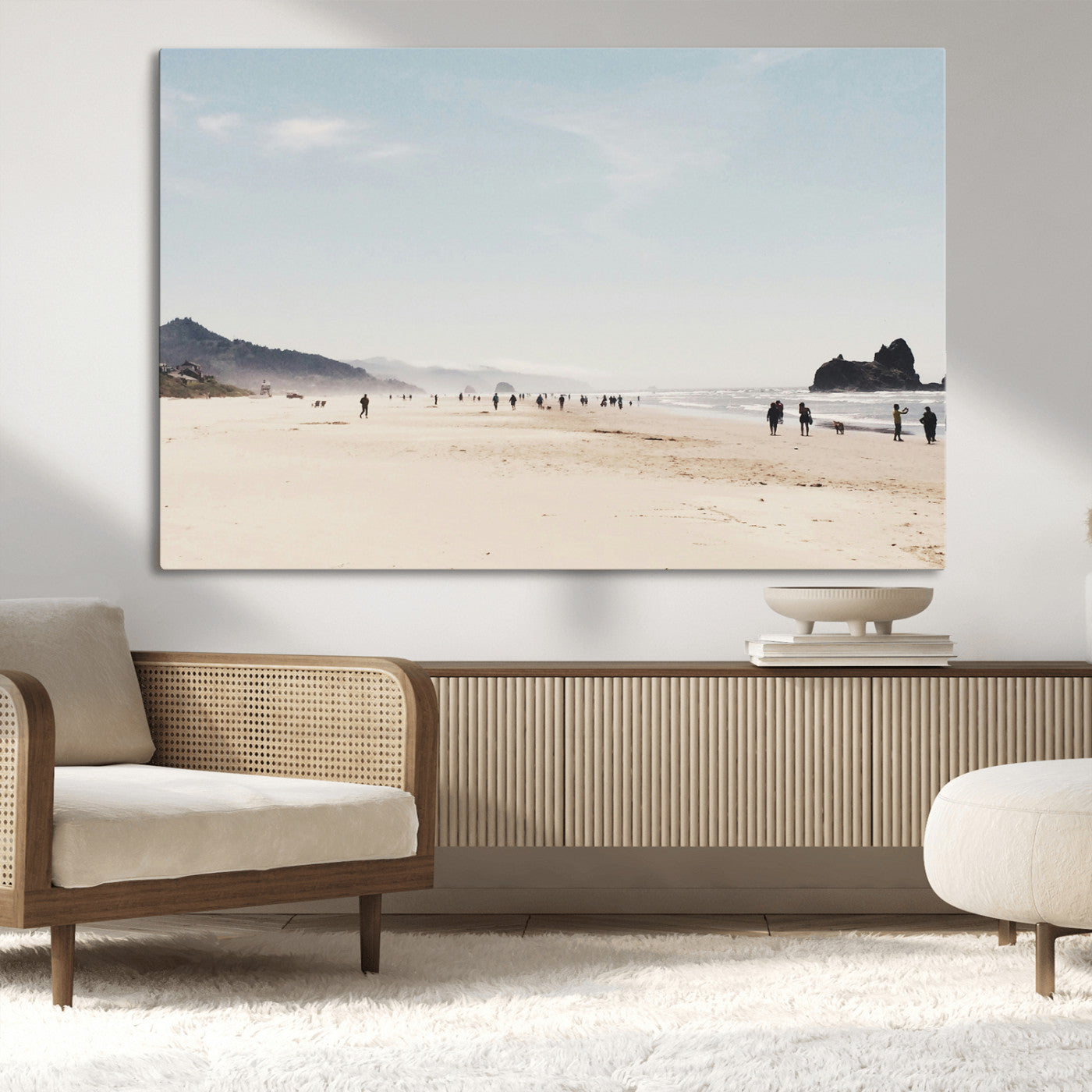 A serene beach with soft sand, misty mountains, and scattered people walking along the shoreline, creating a peaceful coastal landscape.