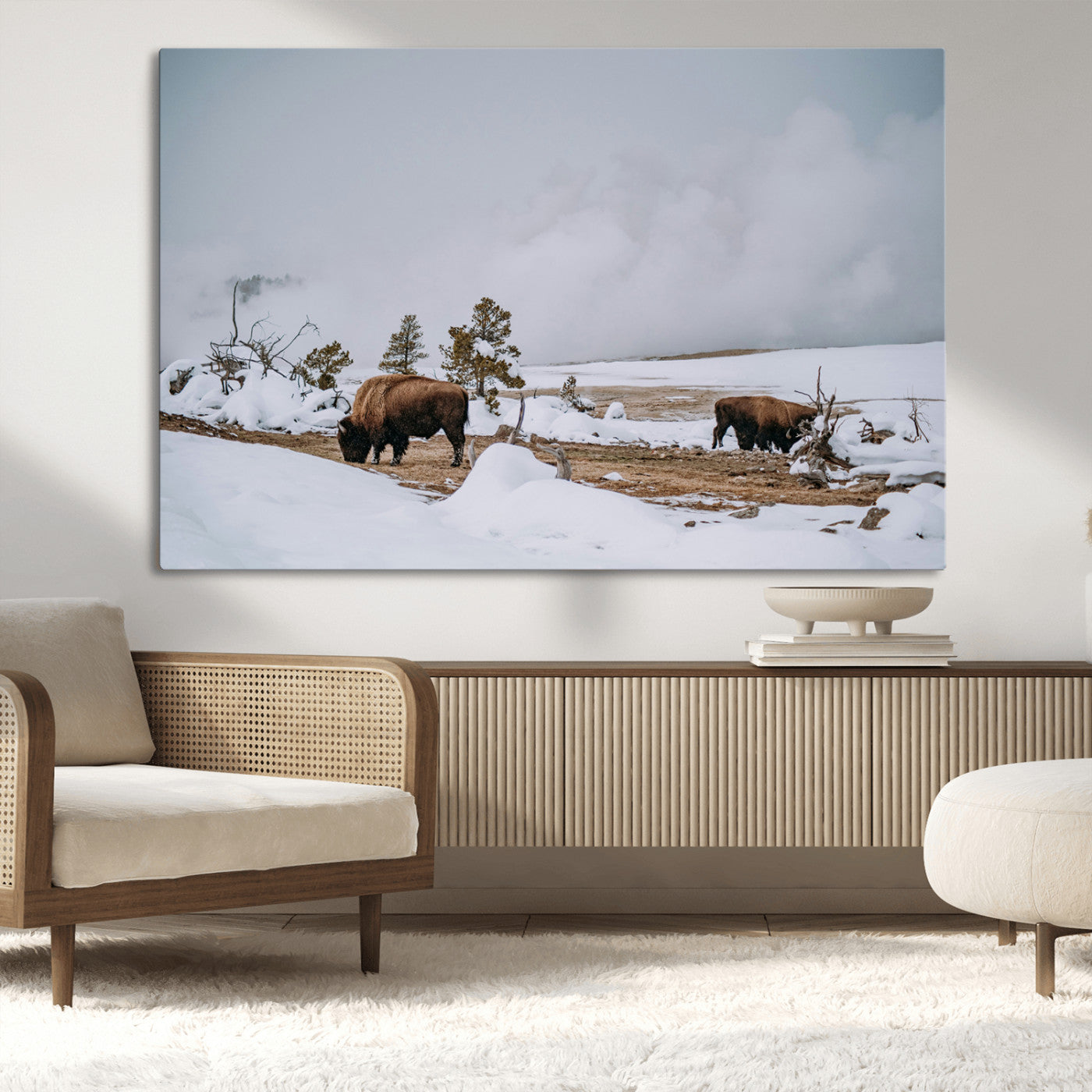 Two bison grazing in a snowy open landscape with misty hills in the background, creating a peaceful and rustic winter scene.
