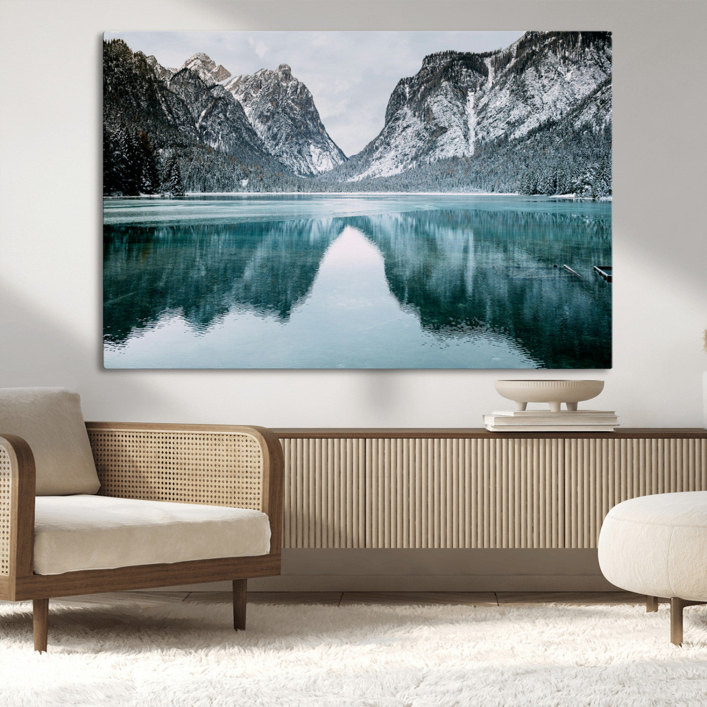 Crystal-clear alpine lake reflecting snow-covered mountains, surrounded by evergreen trees, creating a serene and tranquil winter landscape.