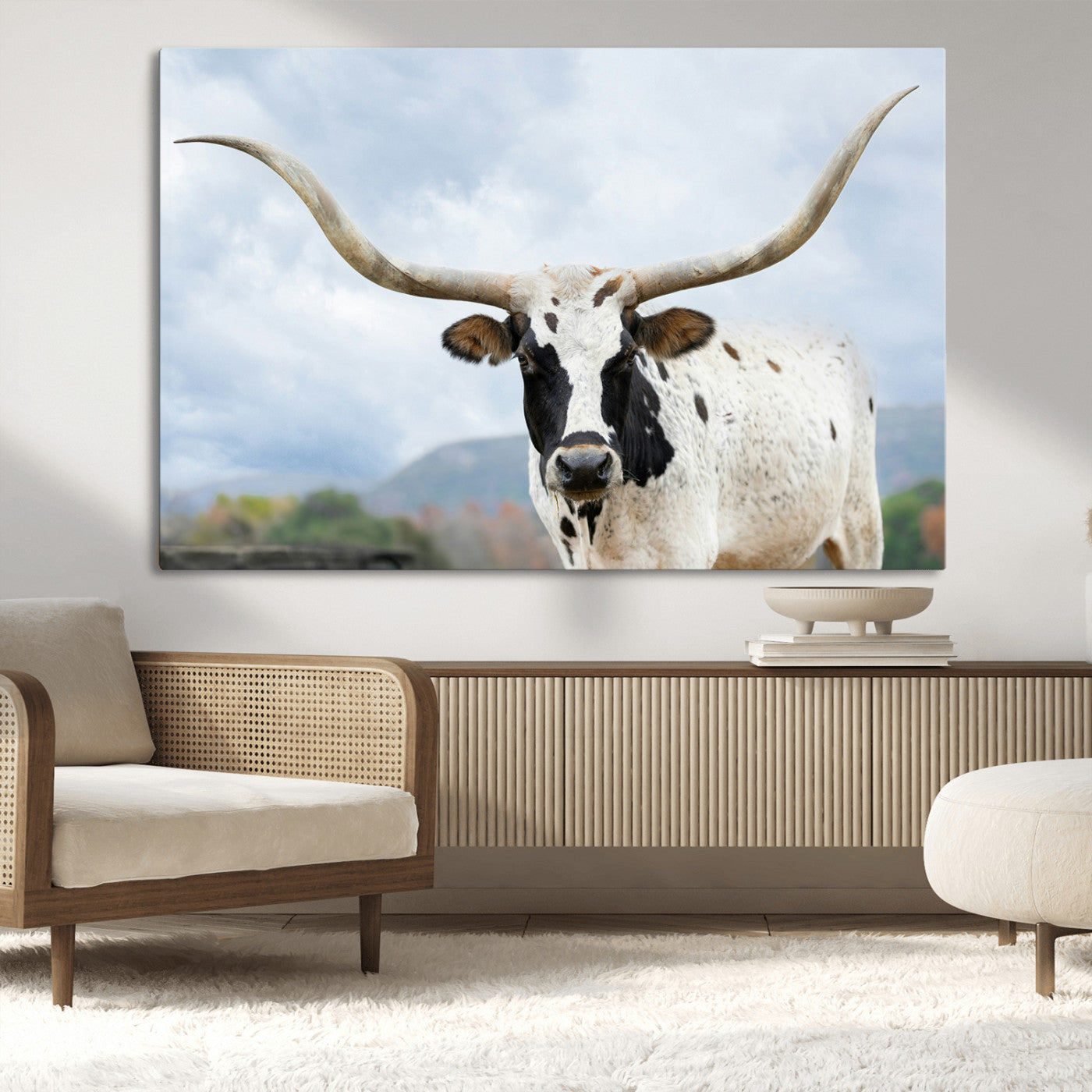 Close-up of a Texas Longhorn with curved horns, black and white markings, set against a cloudy sky and distant hills, perfect for rustic decor.