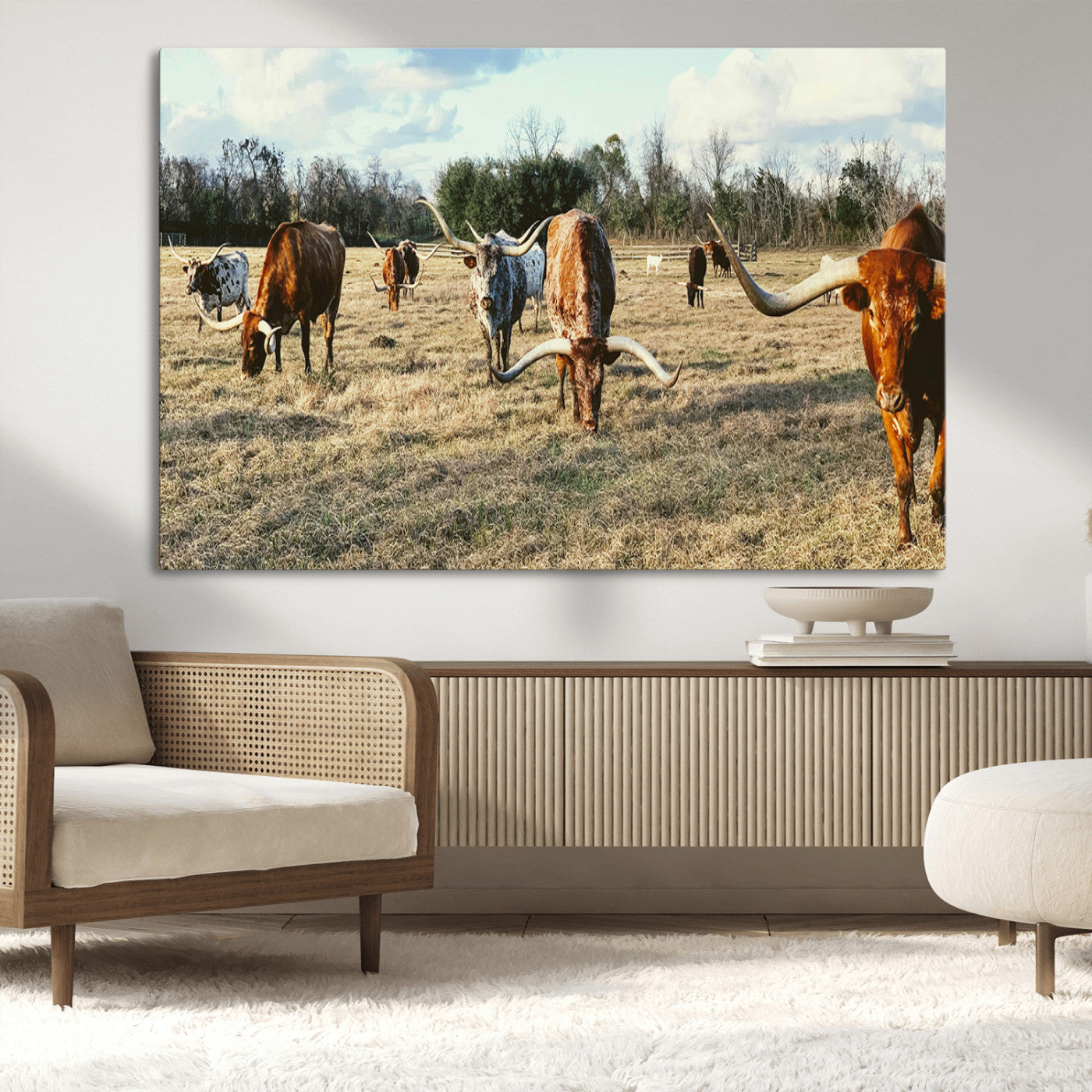A herd of Texas Longhorn cattle grazing in an open field under a partly cloudy sky, capturing a rustic and Western ranch aesthetic.