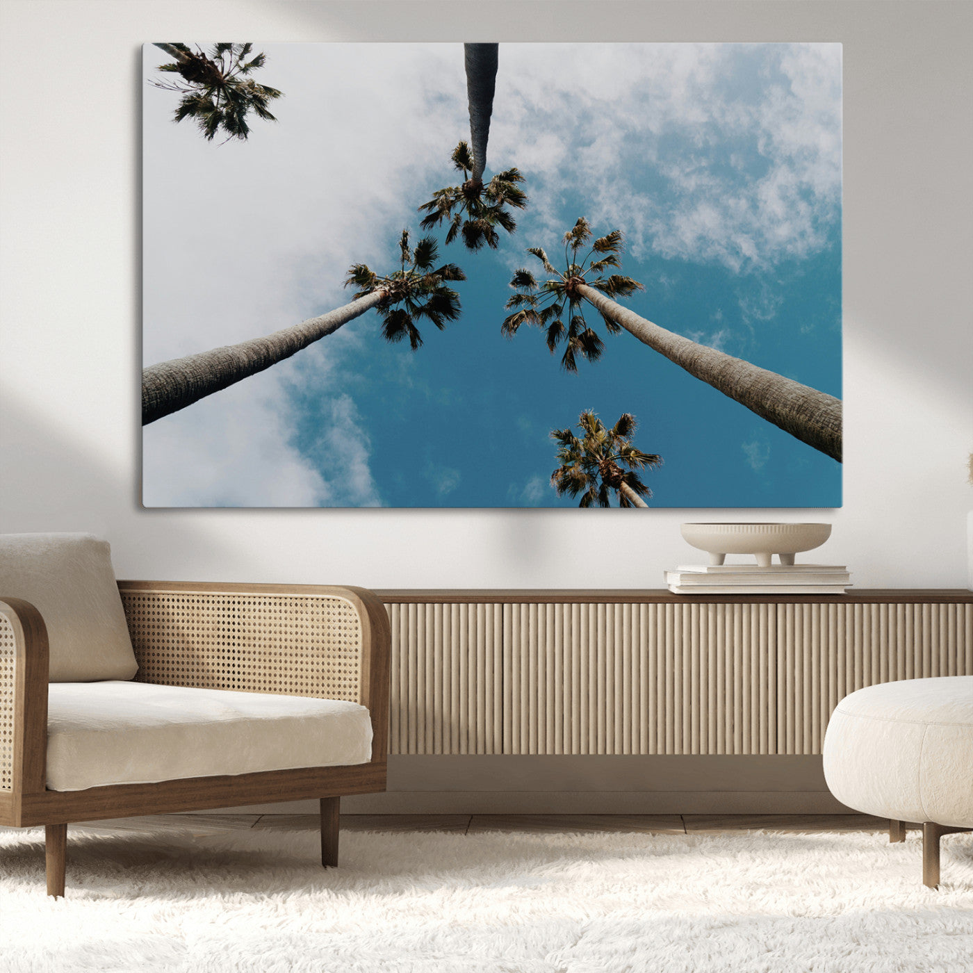 Looking up at tall palm trees against a bright blue sky with scattered clouds, creating a tropical and airy atmosphere for modern home decor.