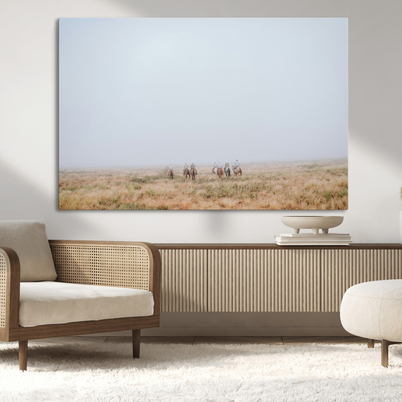A group of horseback riders moving through a fog-shrouded field, evoking a calm Western scene with golden grasses and soft horizons.