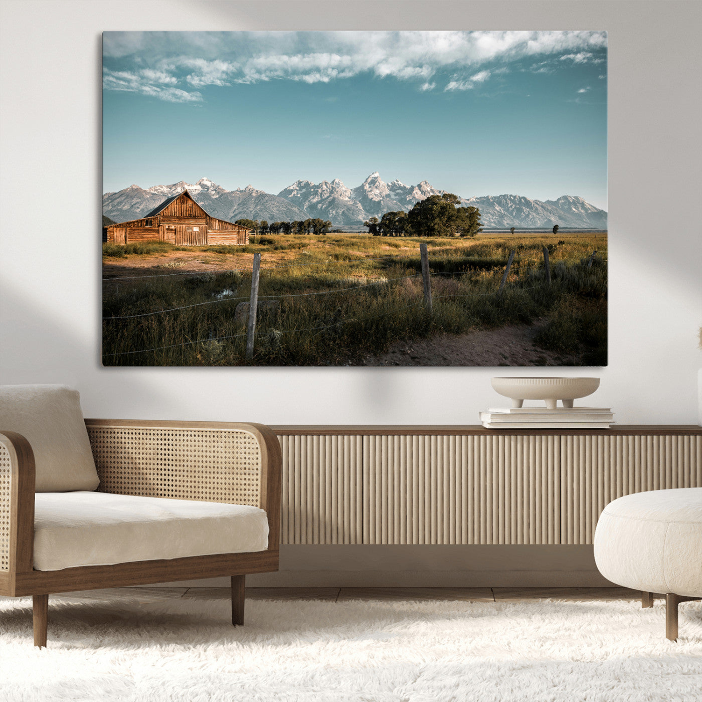 A rustic farmhouse with a wooden barn set against majestic mountain peaks under a soft blue sky, evoking peaceful countryside charm.