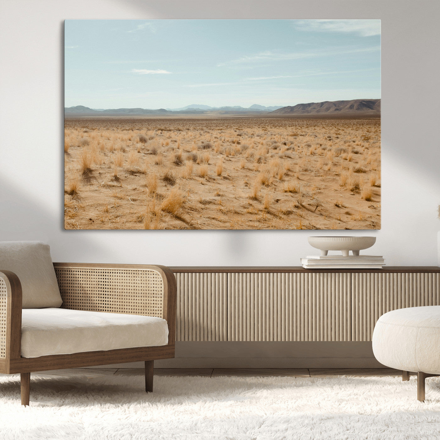 Expansive desert landscape with scattered dry grass and distant mountain range under a pale blue sky – Wall Art Canvas Print.