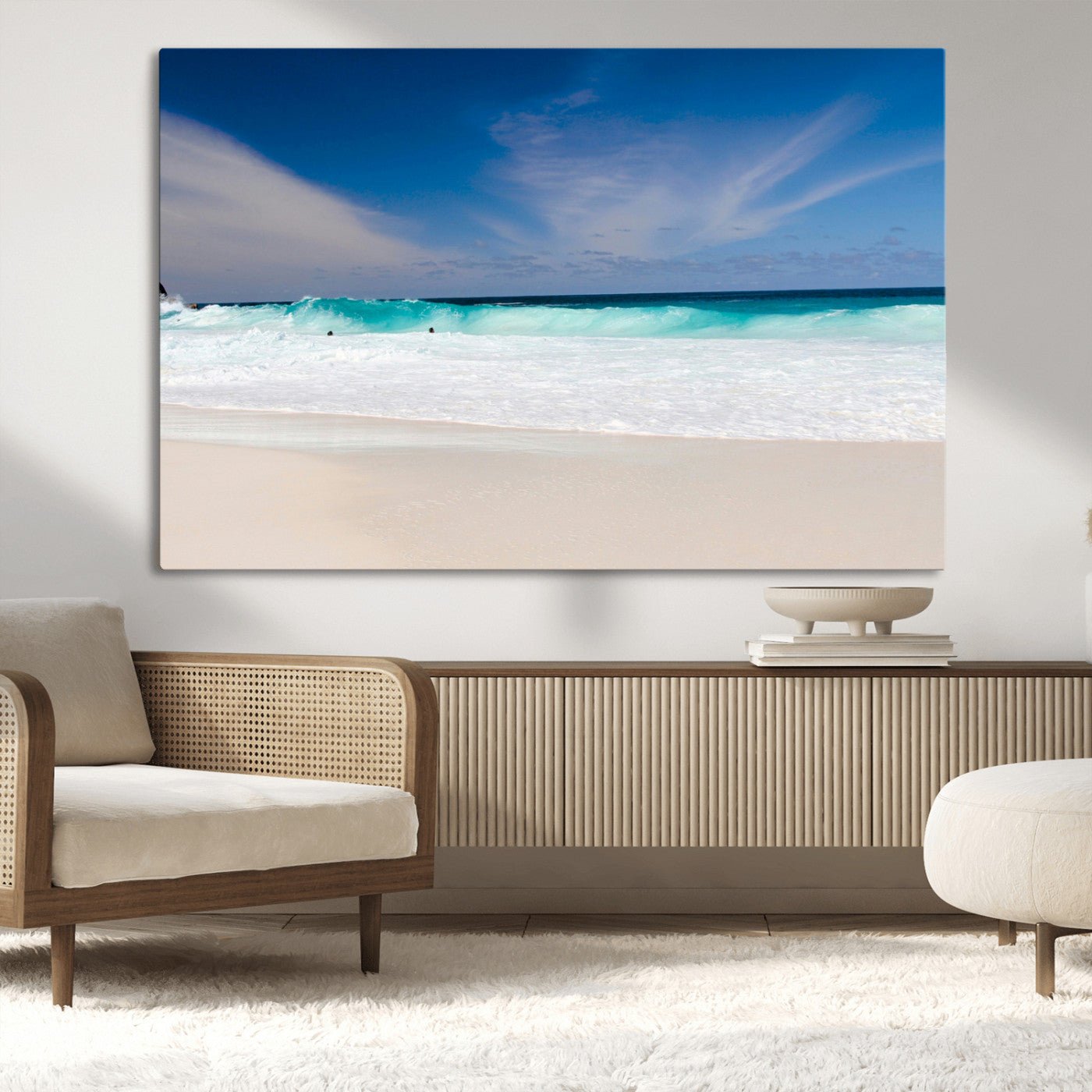 Turquoise waves crash onto a pristine white sand beach under a vivid blue sky with wispy clouds, creating a peaceful and refreshing coastal scene.