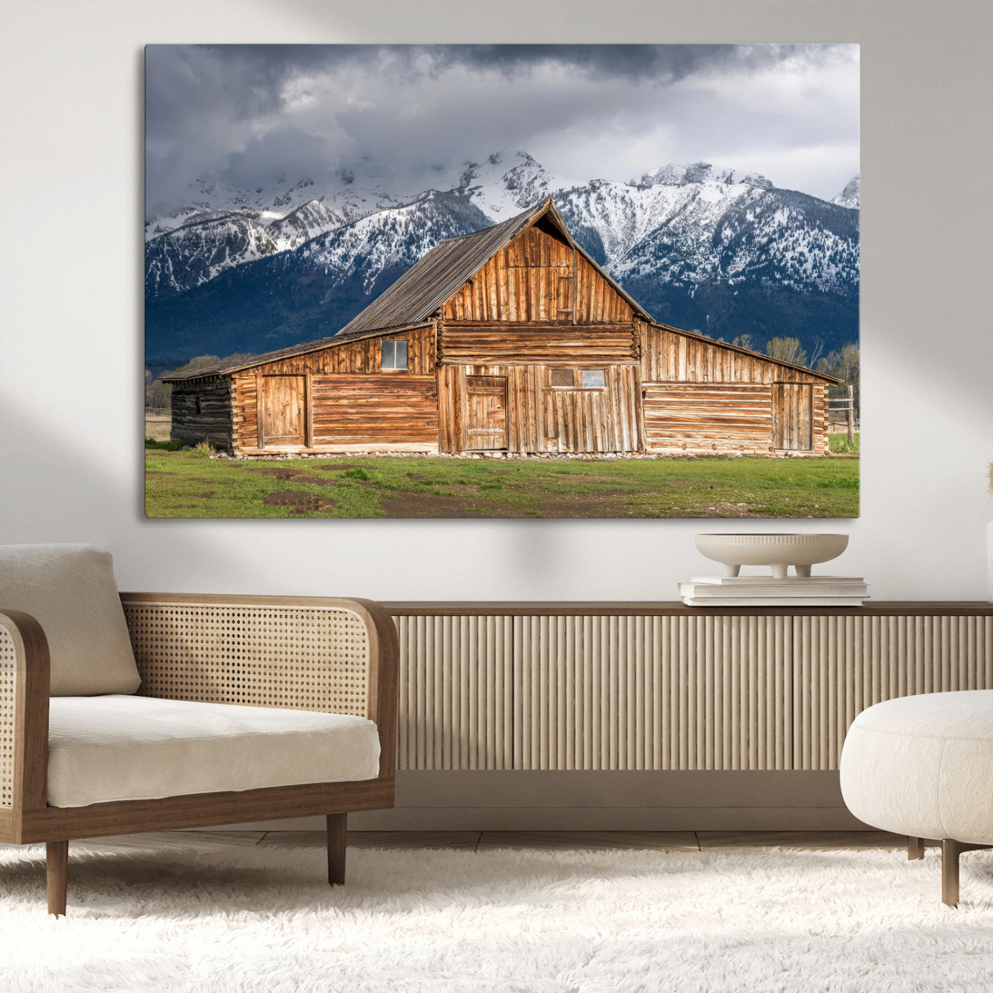 A stunning wall art canvas print featuring a rustic wooden barn set against a backdrop of snow-capped mountains under a dramatic cloudy sky, perfect for adding a touch of rural charm to any space.