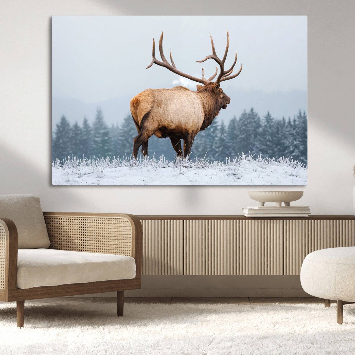 A majestic elk standing in a snowy landscape, with large antlers, set against a backdrop of evergreen trees and a soft winter sky.