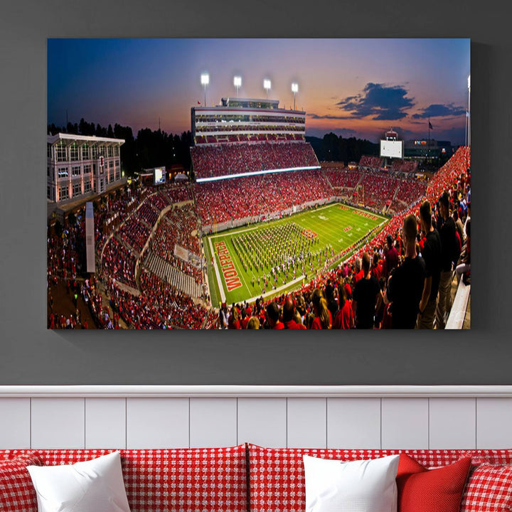 A print of a bustling Carter-Finley Stadium at dusk, featuring fans and a band, captures the essence of NC State Wolfpack football.