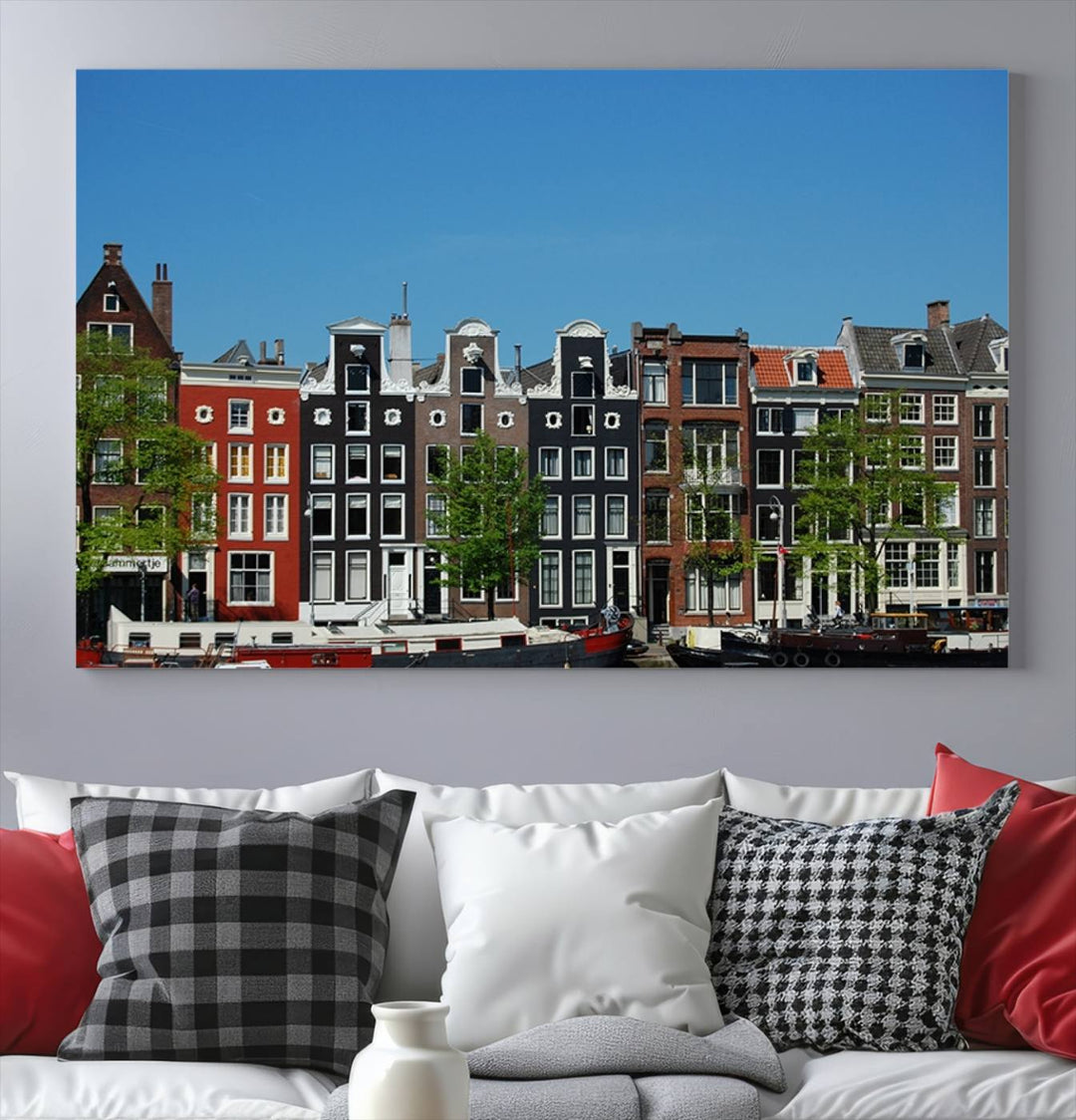 The Amsterdam City Wall Art Canvas Print showcases colorful traditional canal houses and boats set against a clear blue sky.