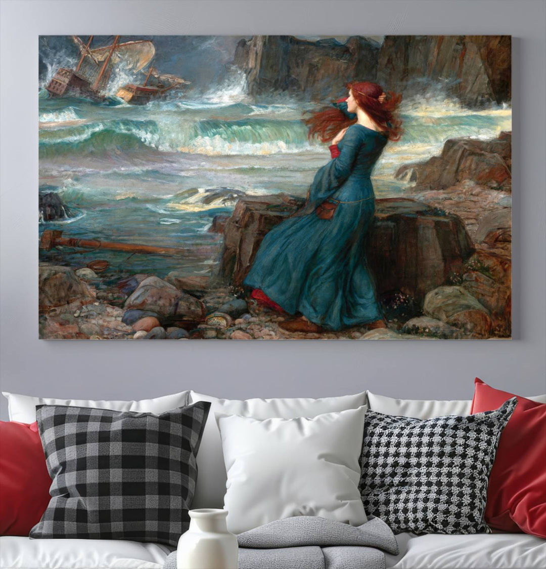 The Miranda by the Shore Wall Art Canvas Print depicts a woman in a blue dress standing by the sea, watching a shipwreck.