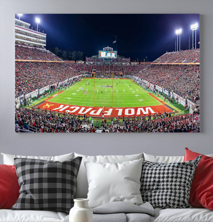 A NC State Wolfpack Football Team print of Carter-Finley Stadium at night features WOLFPACK illuminated brightly in the end zone grass.