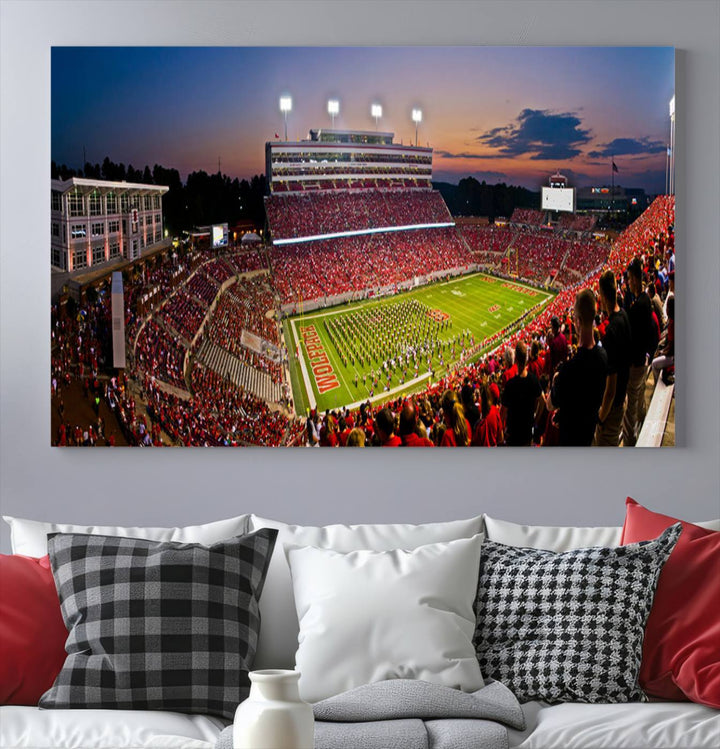 A print of a bustling Carter-Finley Stadium at dusk, featuring fans and a band, captures the essence of NC State Wolfpack football.