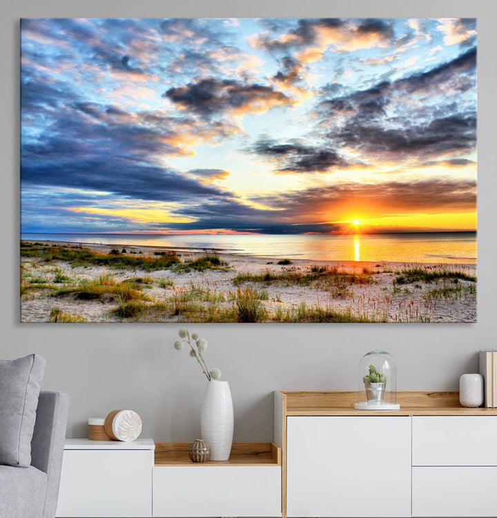 The Sunset On The Ocean canvas wall art features a beautiful beach sunset with grass and clouds.