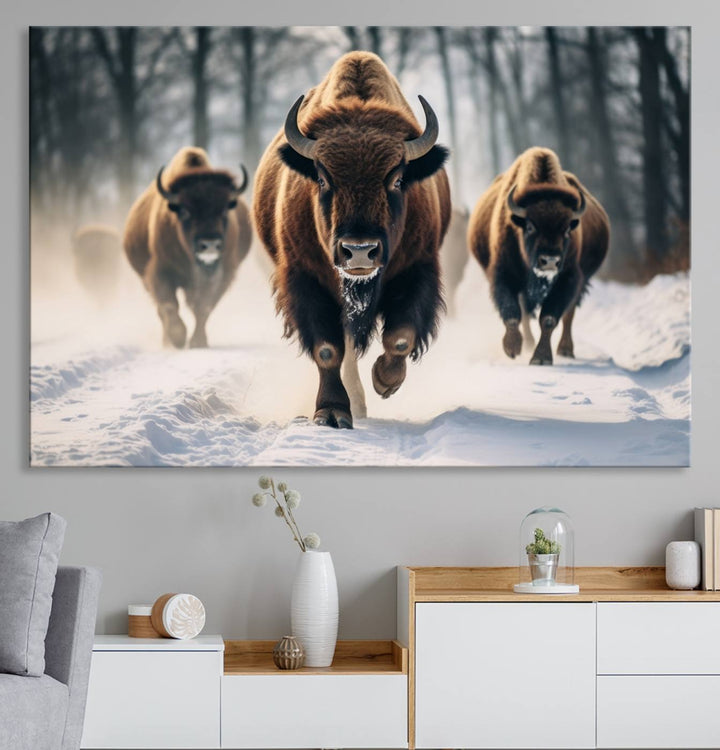 Wall art titled Cow Bighorn shows three bison running through snow in a forest.