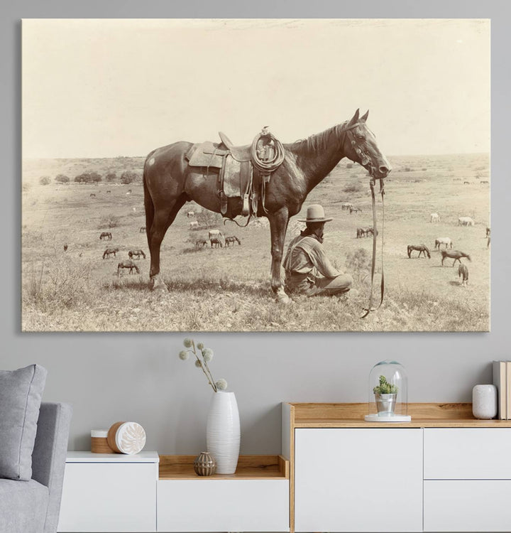 Cowboy Wall Art - Vintage Western Horse Canvas Print features a cowboy kneeling by his horse in a field.