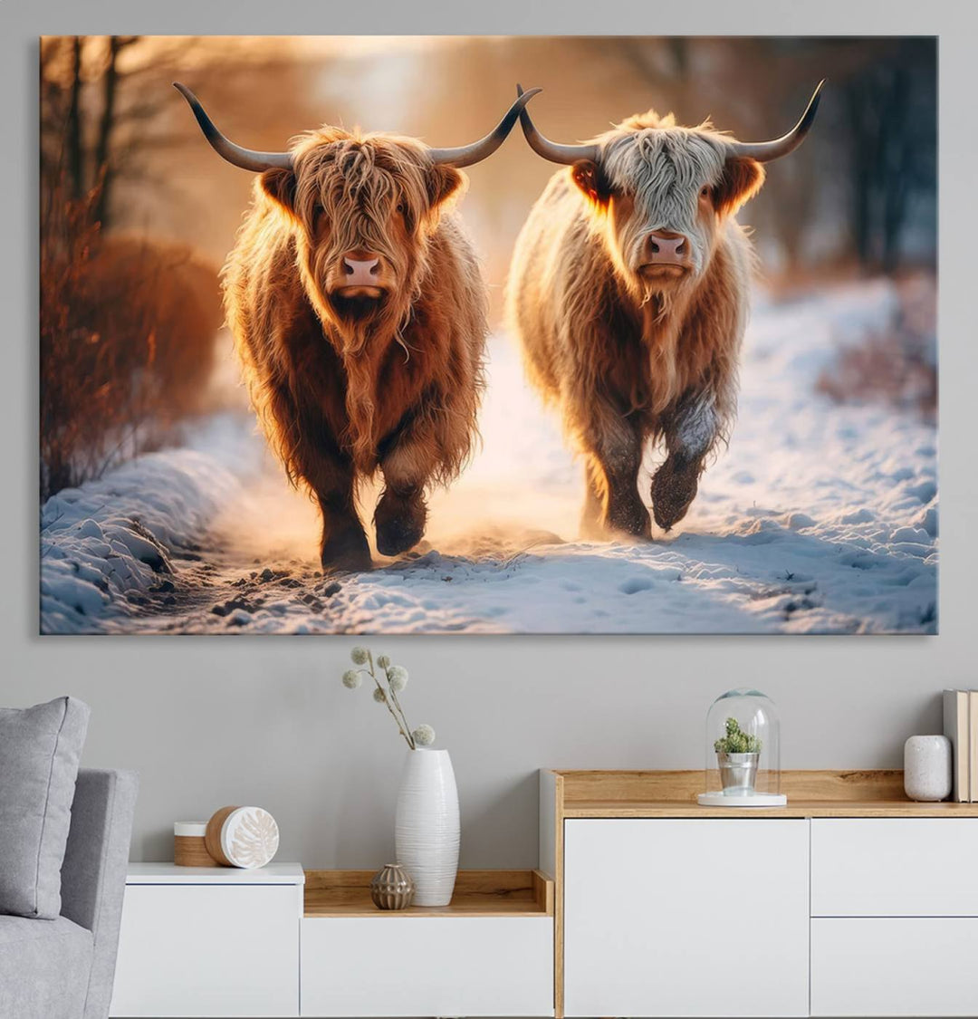 The wall art is a Scottish Highland Cow Horn canvas print featuring cows on a snowy path bathed in warm sunlight, serving as a rustic decor piece.