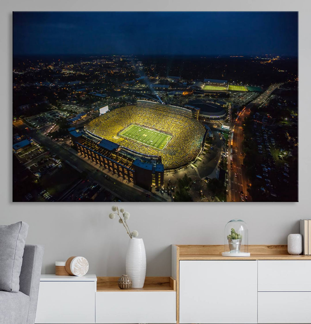 Aerial view of Michigan Stadium at night, surrounded by city lights, depicted on a Michigan Wolverines wall art canvas print.