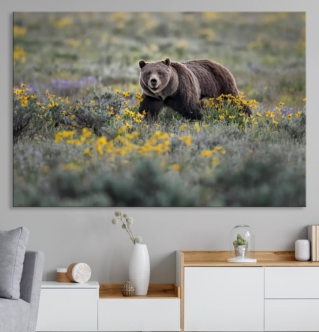 The "Grizzly 399 in Wild Flowers Wall Art Canvas Print" features a grizzly bear strolling through a field of yellow and purple flowers, beautifully showcased as a triptych. This handcrafted piece, proudly made in the USA, adds charm and sophistication to your space.