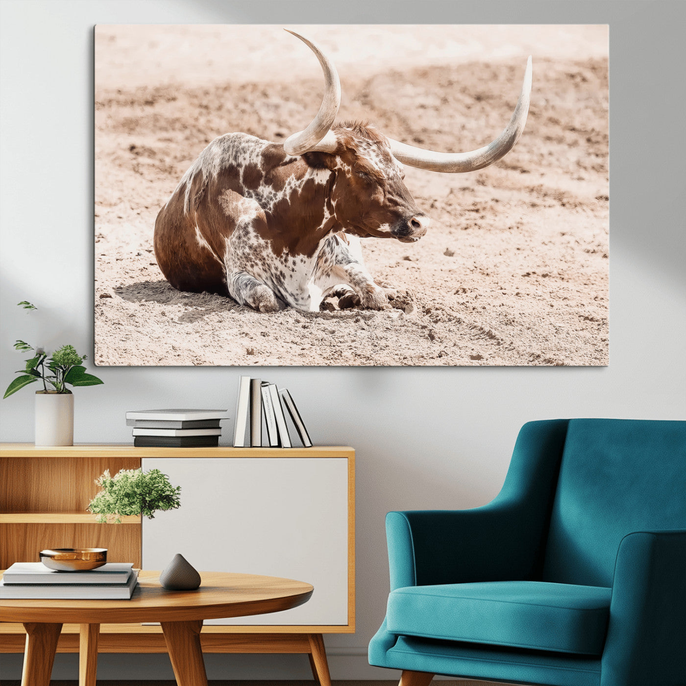 Texas Longhorn bull resting on dusty ground with warm tones, ideal for rustic western or farmhouse-themed wall decor.