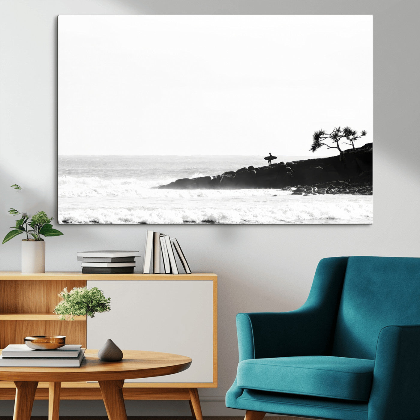 Black and white photo of a surfer standing on rocky cliffs, gazing at the waves, embodying the spirit of adventure and solitude.