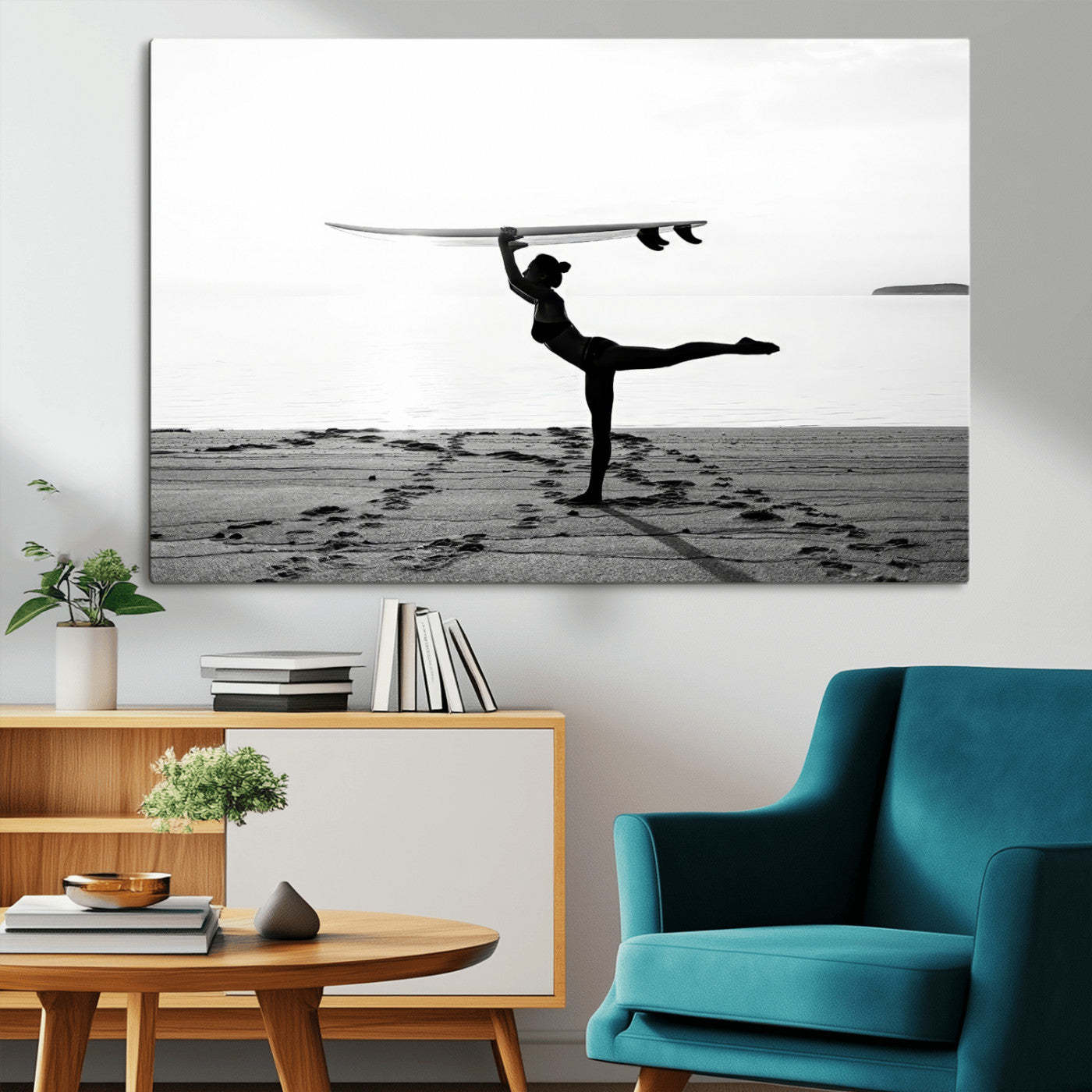 A woman balances a surfboard on her head while striking a yoga pose on the beach, silhouetted against a calm ocean horizon.