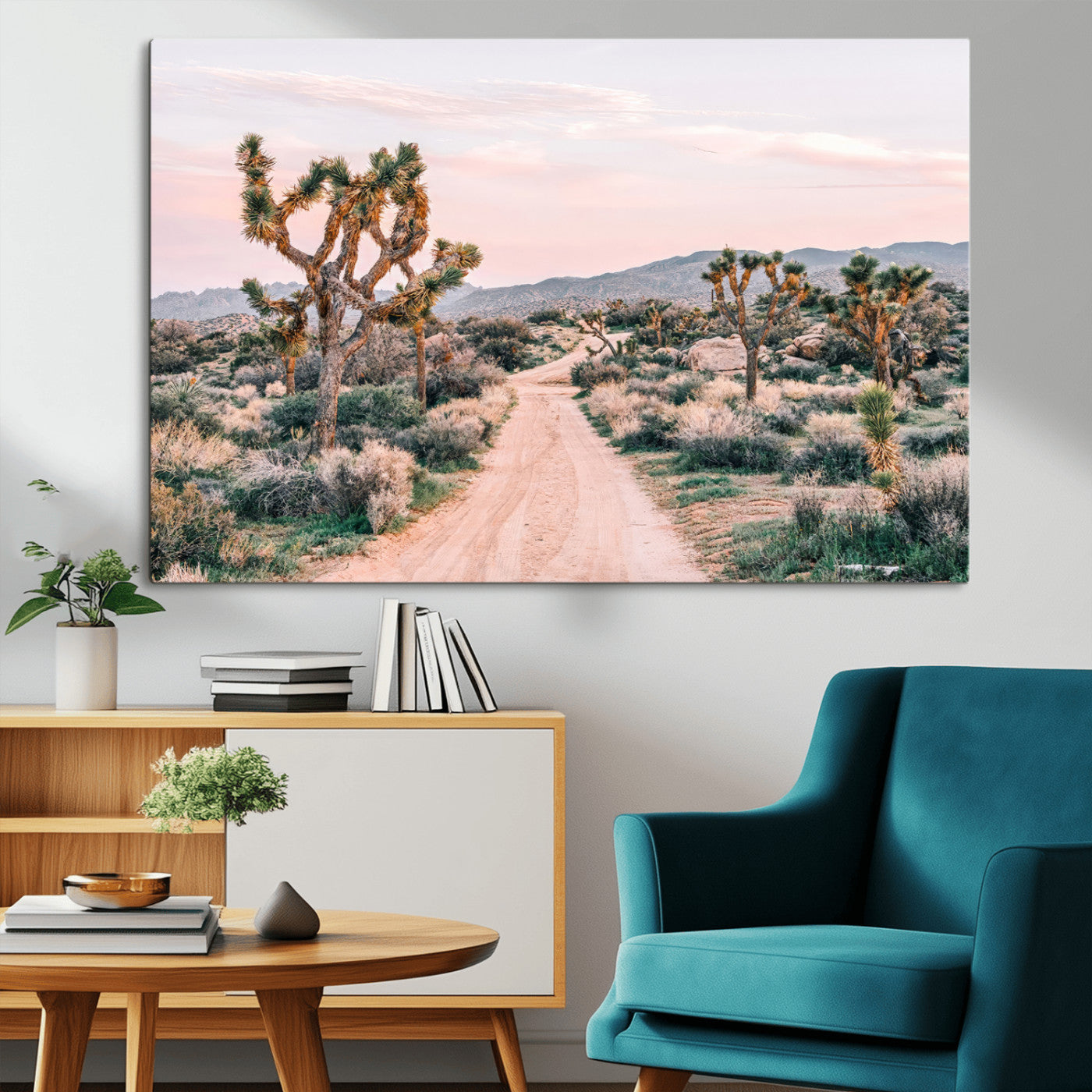 A dusty road winding through Joshua Tree National Park, framed by iconic twisted trees and warm desert tones under a soft pastel sky.