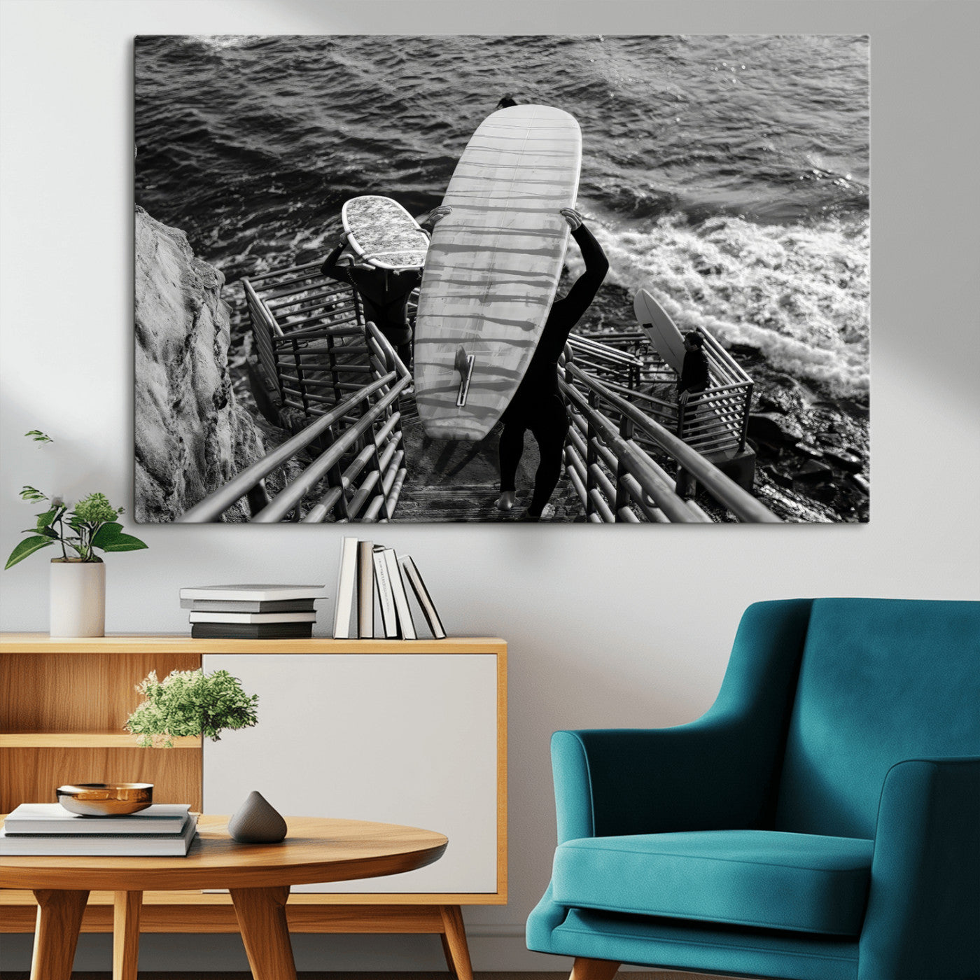Black and white photo of surfers carrying boards down a rugged cliffside stairway, capturing a bold and adventurous coastal scene.