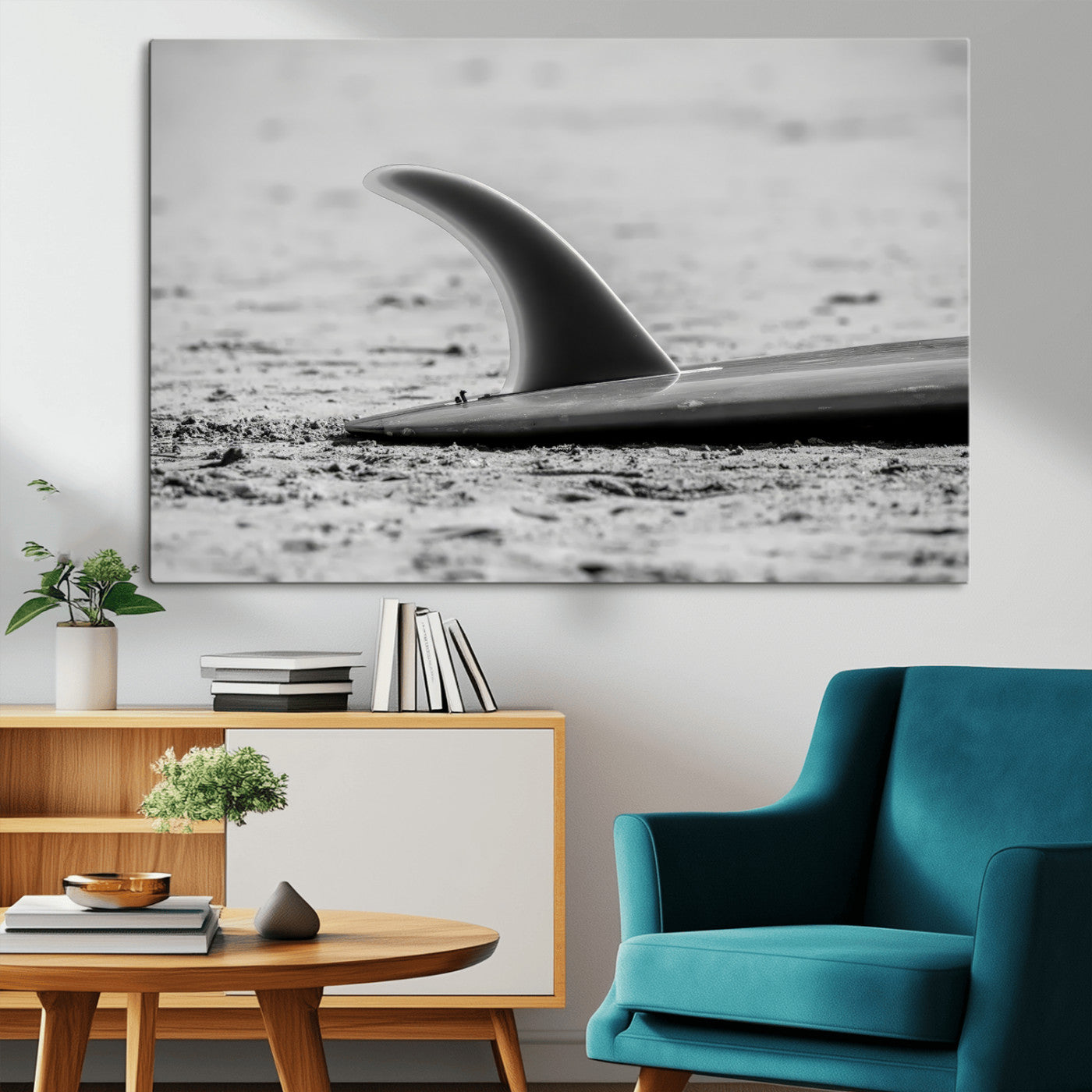 A black and white close-up of a surfboard fin resting on the sandy shore, highlighting minimalist beach aesthetics and classic surf culture.