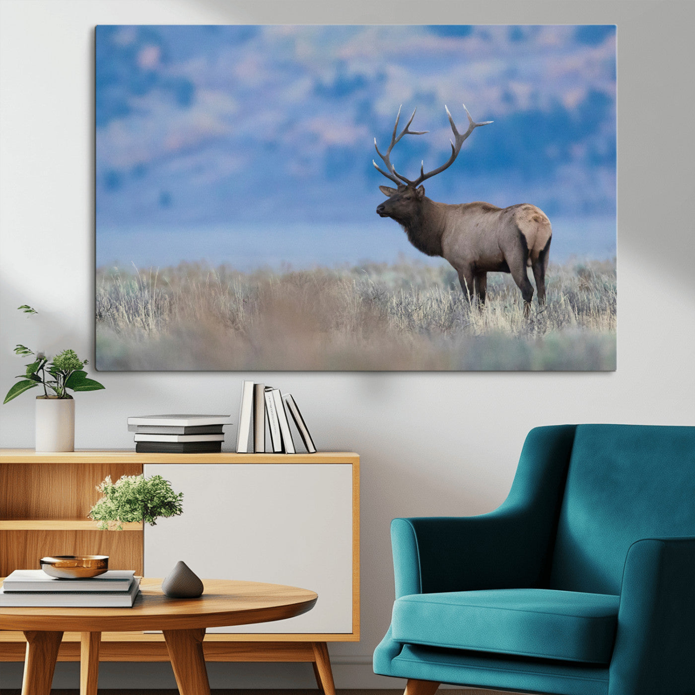 Elk with large antlers standing in open field, mountains blurred in background, perfect for rustic cabin or lodge-style decor.