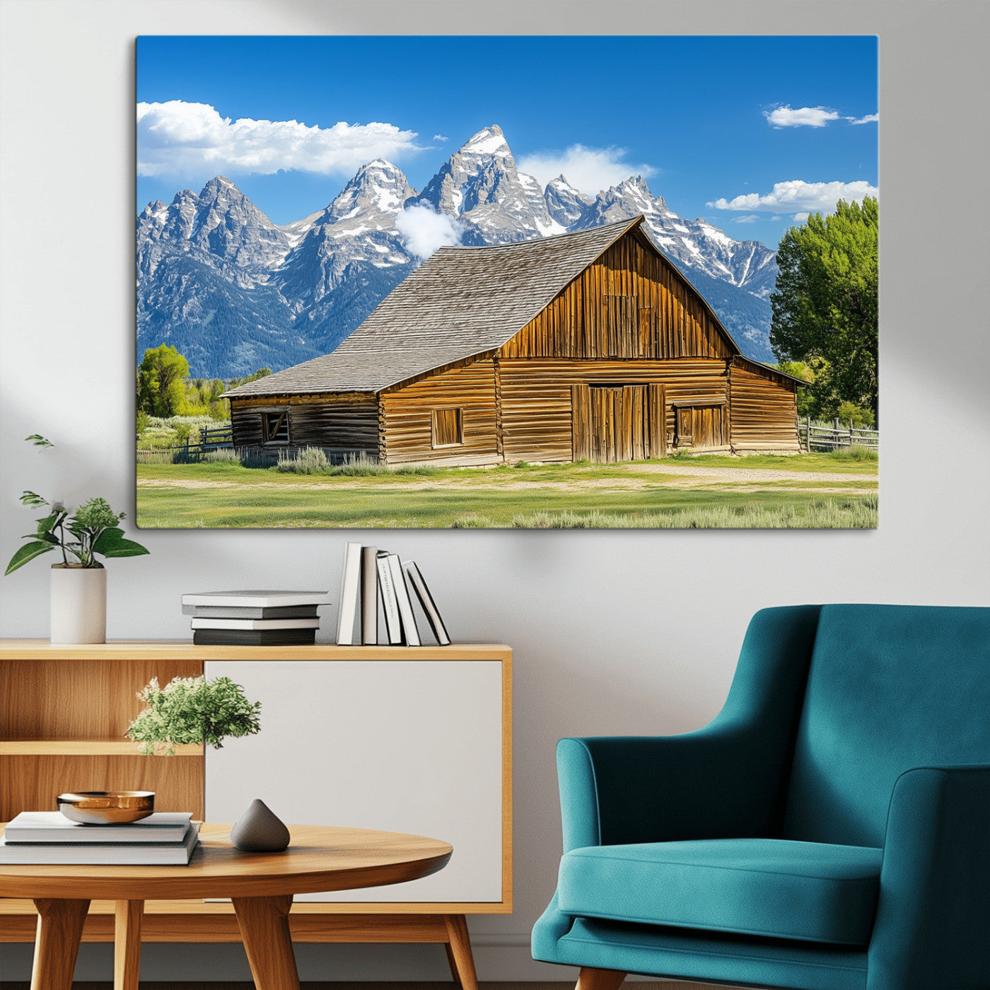 A rustic wooden barn sits in front of towering mountain peaks under a clear blue sky, perfect for farmhouse or cabin style interiors.