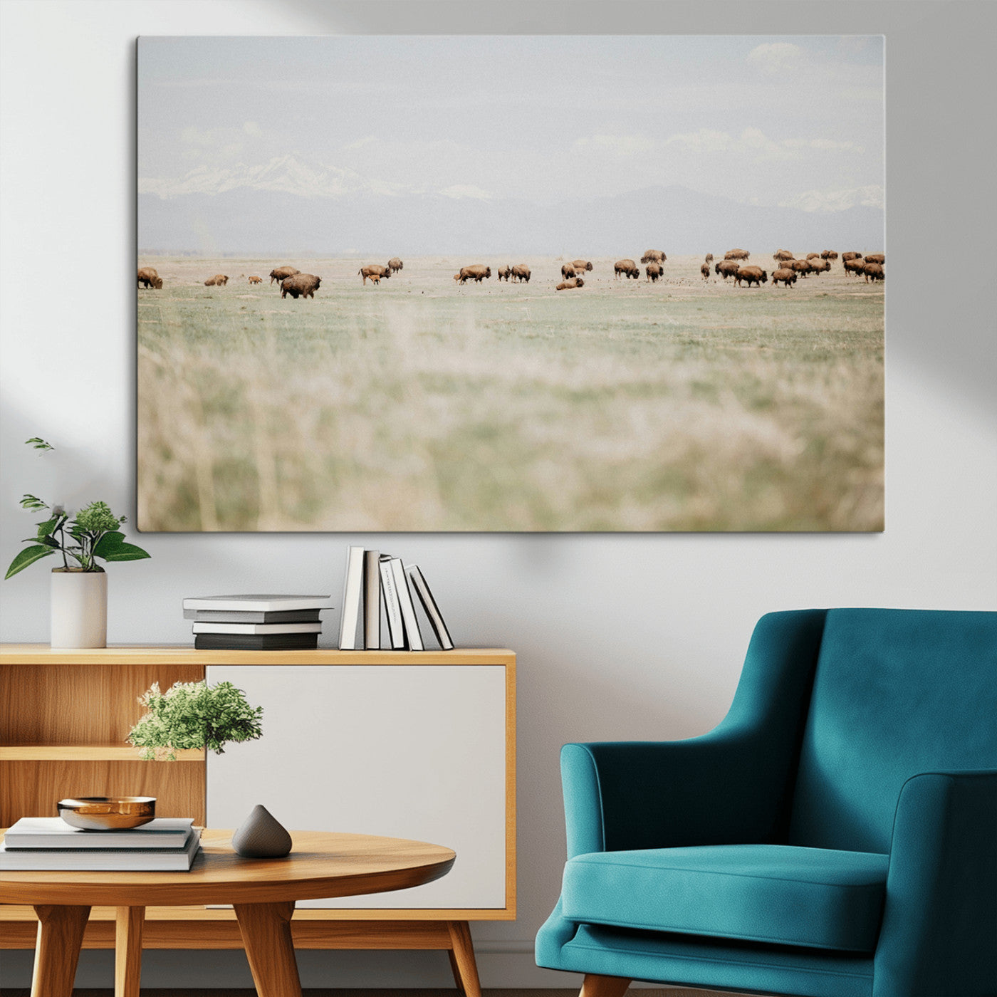 A herd of bison grazing in an open prairie with distant mountains under a soft sky, creating a serene and rustic Western landscape.